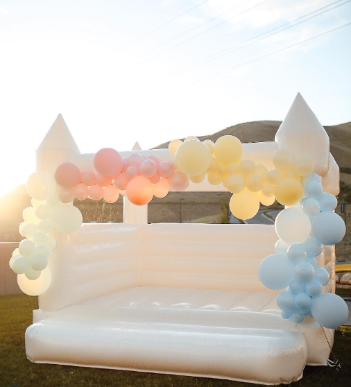 White bounce castle decorated with pastel balloon garlands